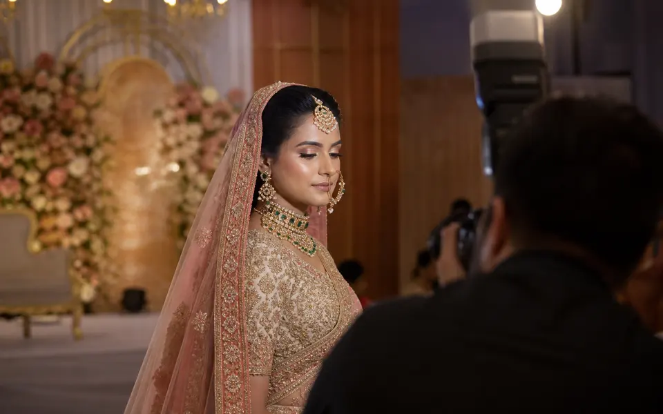 Indian bride on a decorated wedding stage under bright lights, with a softly matte T-zone and gentle glow on the cheeks.