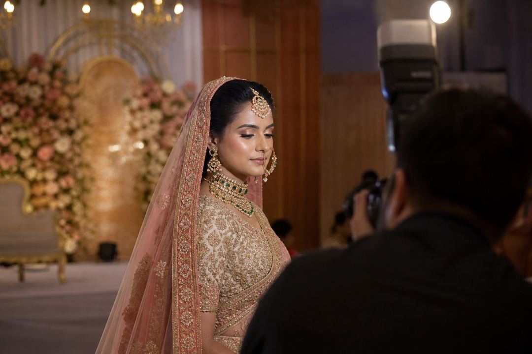 AI-generated illustration: Indian bride on a decorated wedding stage under bright lights, with a softly matte T-zone and gentle glow on the cheeks.