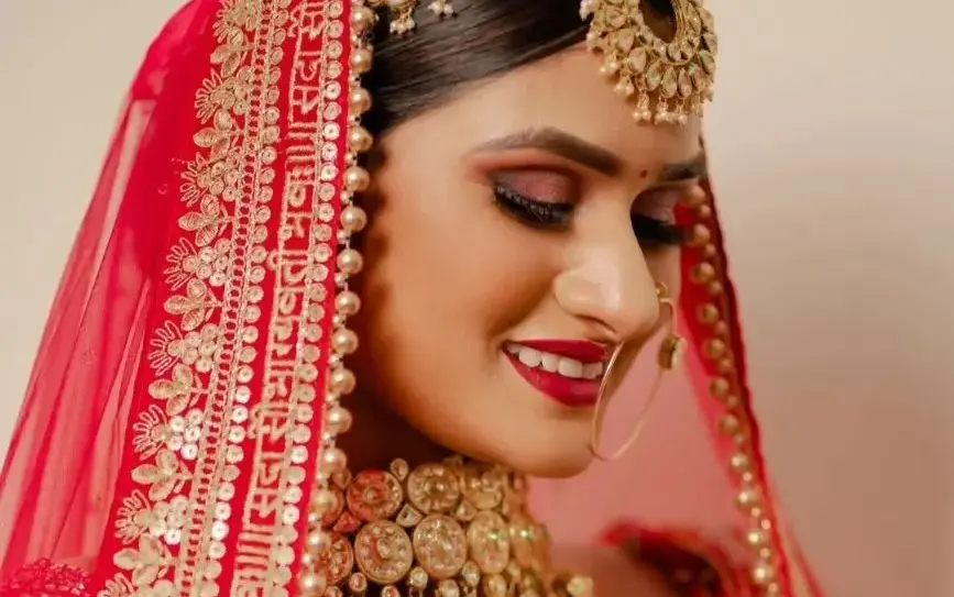Lovely Jaiswal portfolio portrait showing defined warm eyes and a red lip with red bridal clothing.