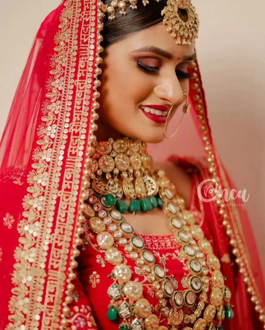 Lovely Jaiswal portfolio portrait showing defined warm eyes and a red lip with red bridal clothing.
